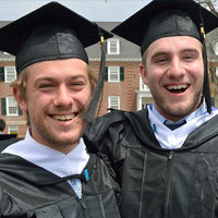 Two graduates posing in their caps and gowns