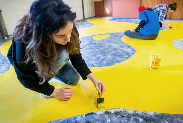 Colby-Sawyer art students paint an abstract design onto commercial floor
