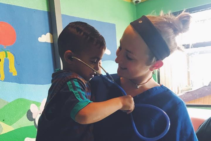 Brittany Ireland holds a little boy as he uses a stethoscope to listen to her heart.